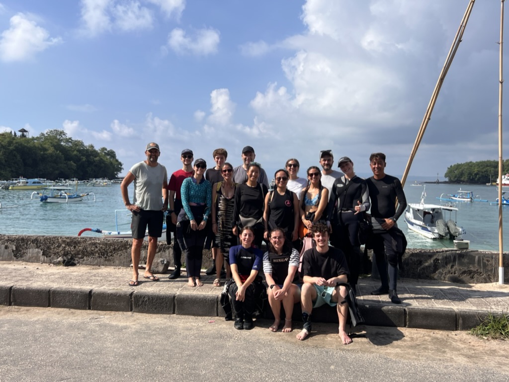Photo de groupe des participants devant le port de Padang Bai après une plongée de restauration