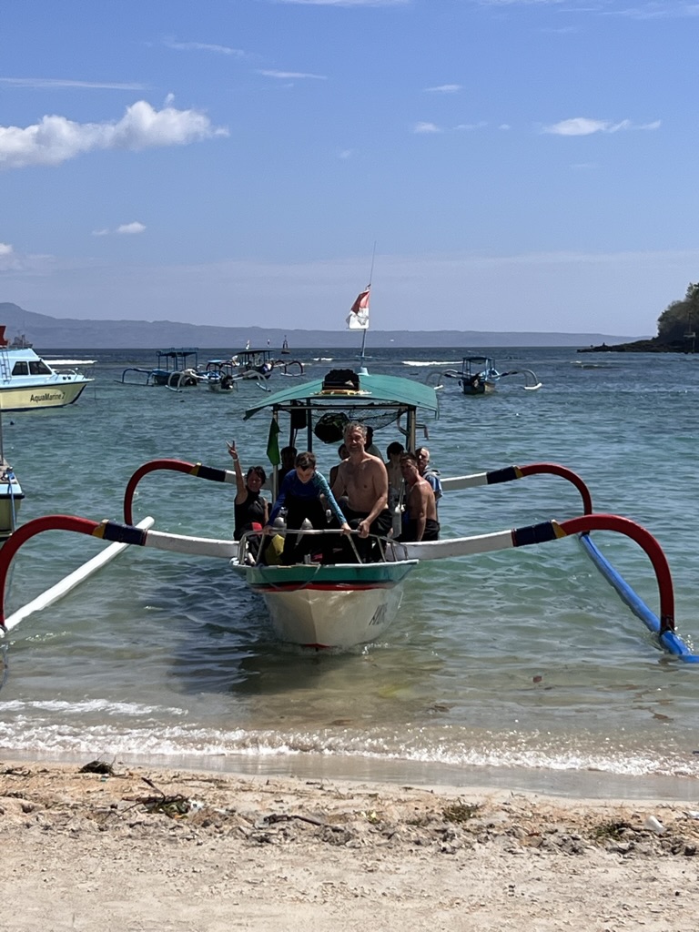 Jukung balinais sur la plage de Padang Bai avec les participants à bord