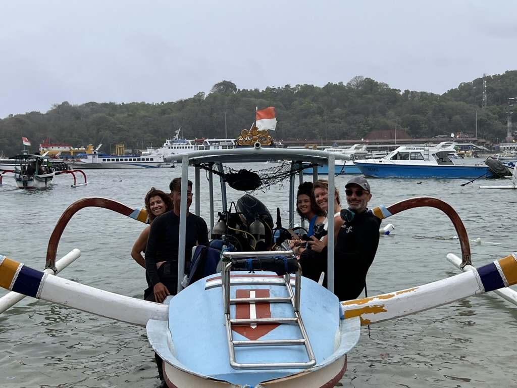 Plongeurs souriants à bord d'un jukung traditionnel dans le port de Padang Bai